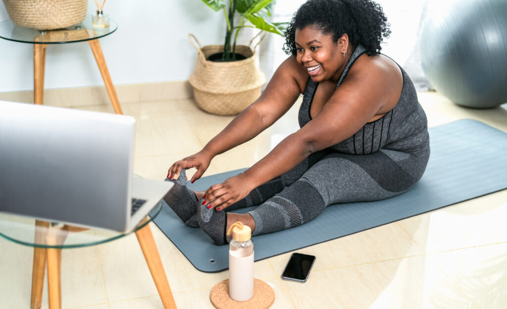 young african curvy woman doing pilates online fitness class with laptop at home sport wellness people lifestyle concept young african curvy woman doing pilates online fitness class with laptop at home sport wellness people lifestyle concept